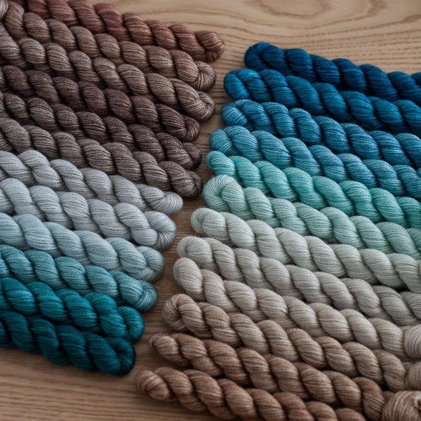 Colorful yarn skeins arranged in a pattern on a wooden surface