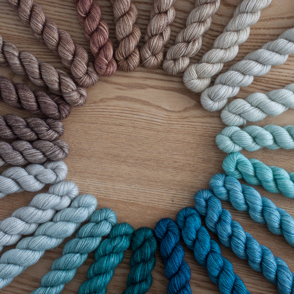 Colorful yarn skeins arranged in a circular pattern on a wooden surface